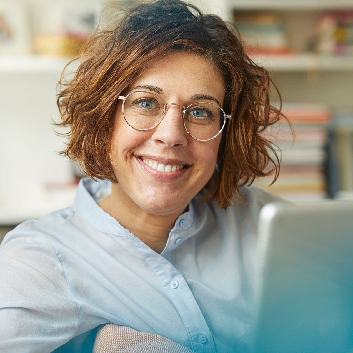 Frau mit Brille lächelt fröhlich in die Kamera