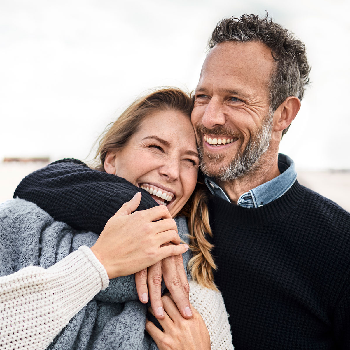 Mann und Frau halten sich lächelnd im Arm
