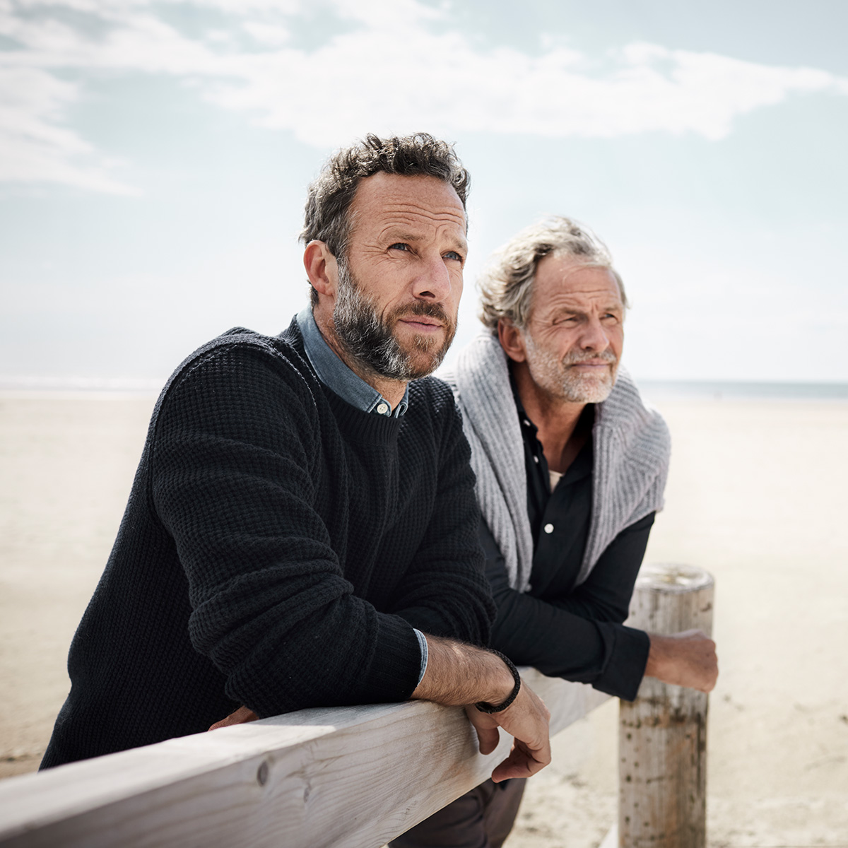 Zwei Männer stehen am Strand und schauen in die Ferne