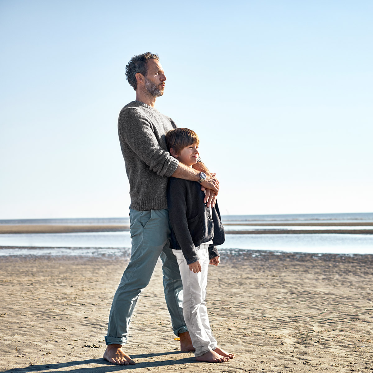 Mann und kleiner Junge stehen am Strand