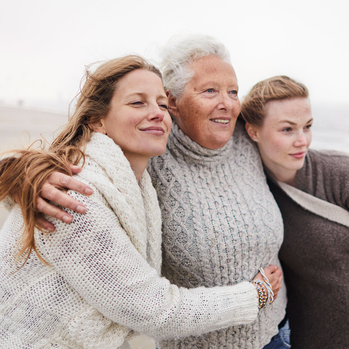 Drei Frauen umarmen sich am Strand