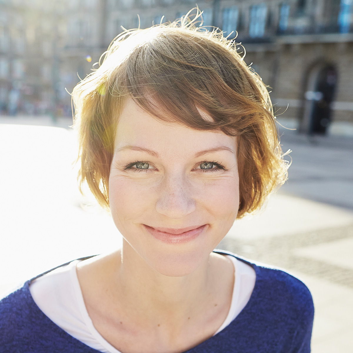 Frau mit Sommersprossen grinst in die Kamera