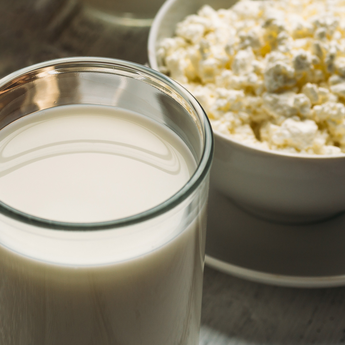 Glas Milch und Schale mit körnigem Frischkäse