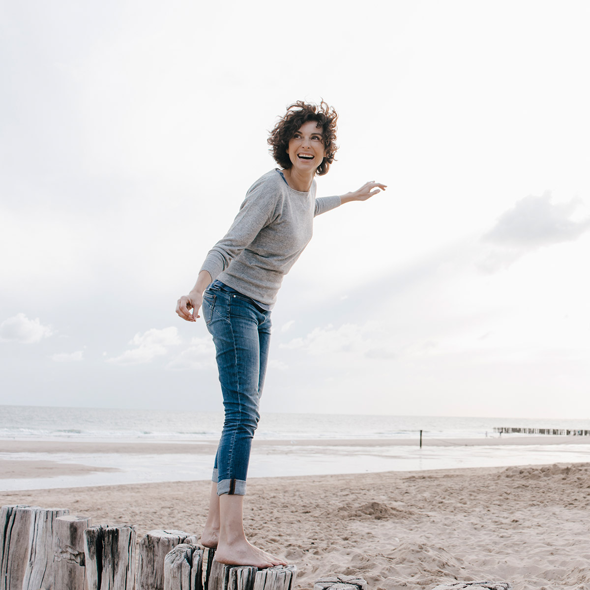Frau steht am Strand auf Holzpfeilern Frau steht am Strand auf Holzpfeilern