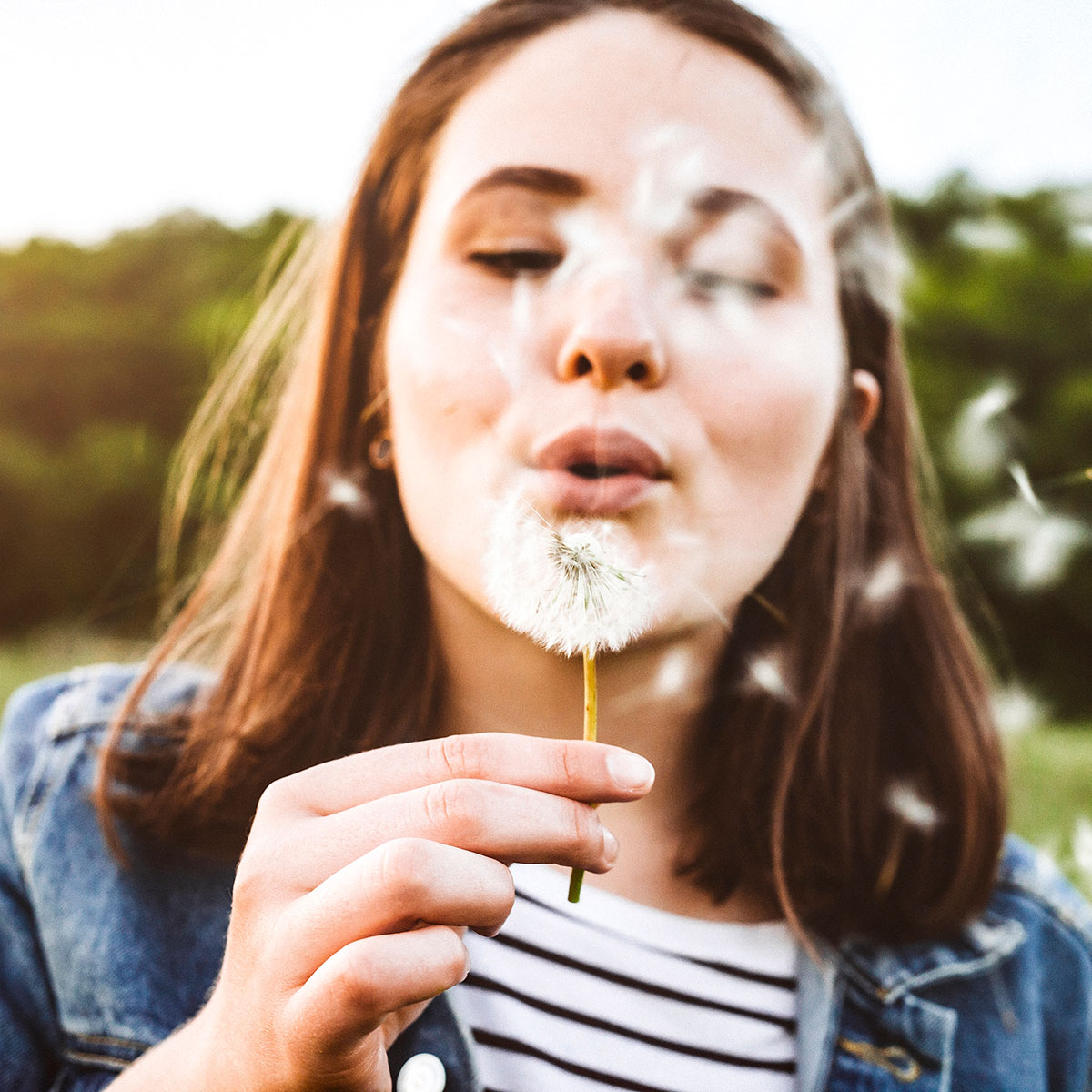 Frau pustet Pusteblume
