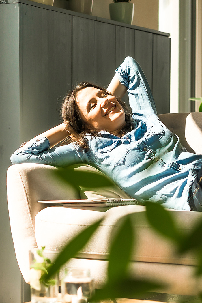 Frau genie&szlig;t Sonne auf dem Sofa