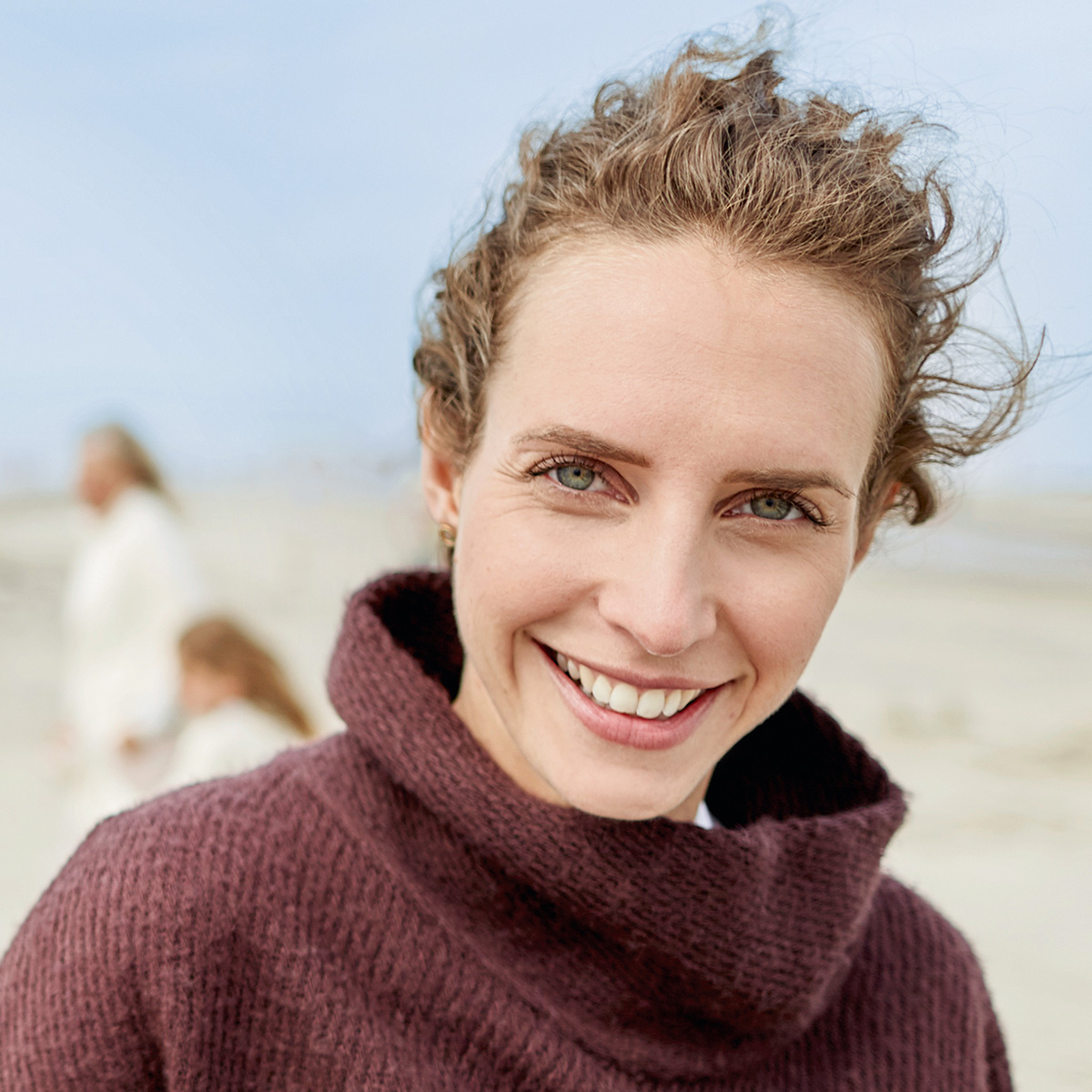 Frau am Strand lächelt in die Kamera