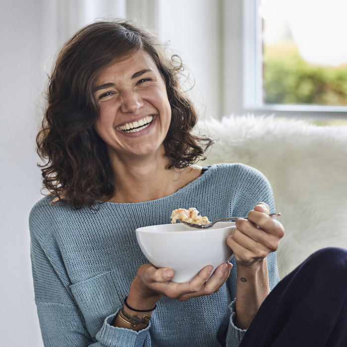 Frau entspannt beim Fr&uuml;hst&uuml;ck mit ballaststoffreichem M&uuml;sli 