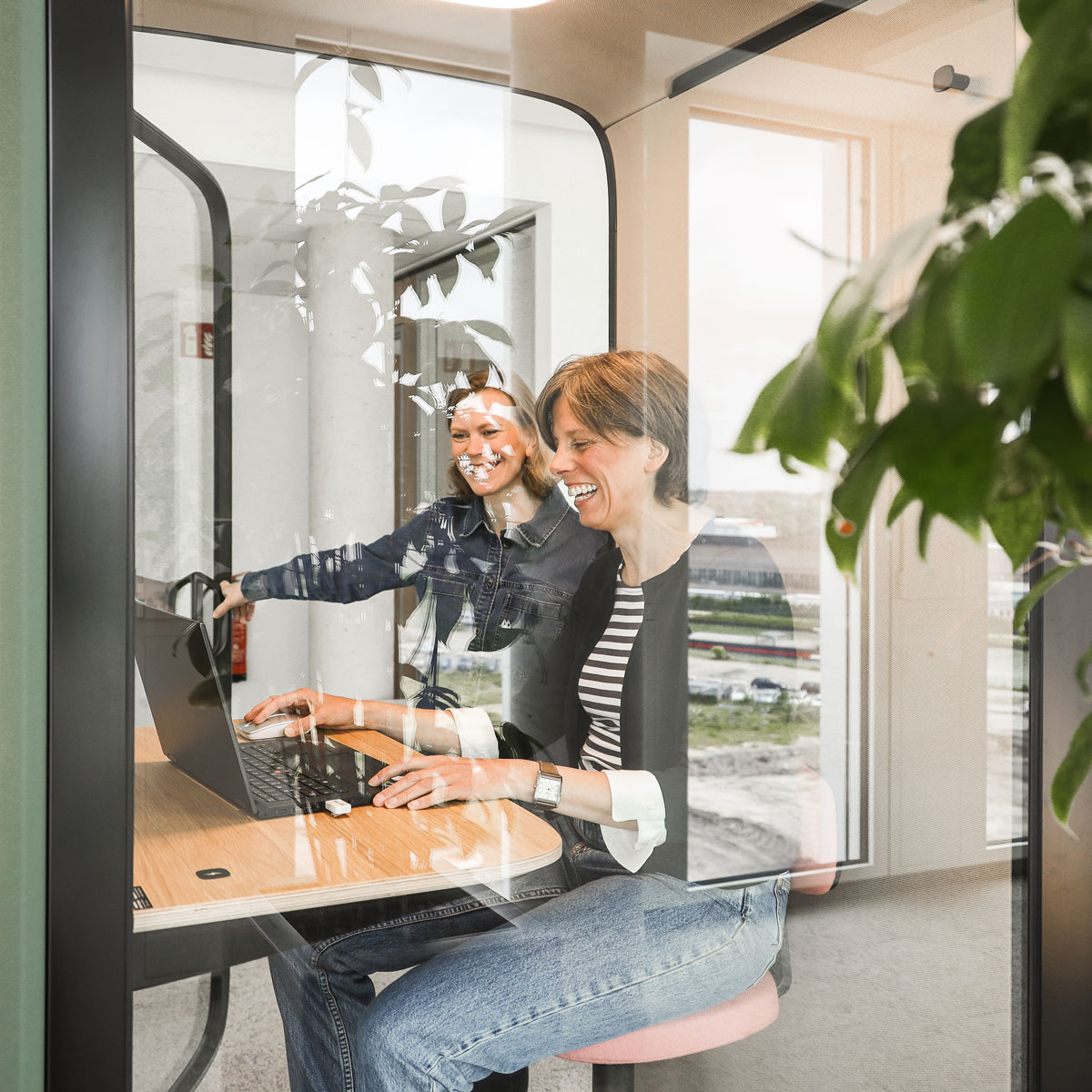 Zwei Mitarbeiterinnen schauen lachend auf einen Laptop