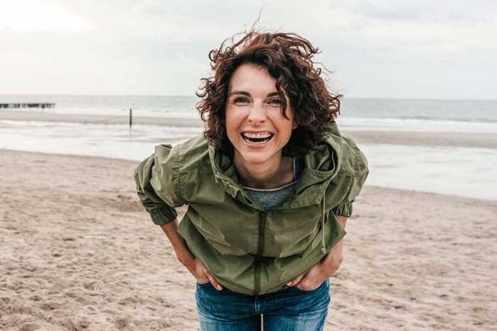 Gl&uuml;ckliche Frau steht am Strand