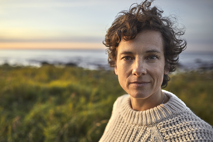 Frau mit kurzen Haaren steht vor dem Meer