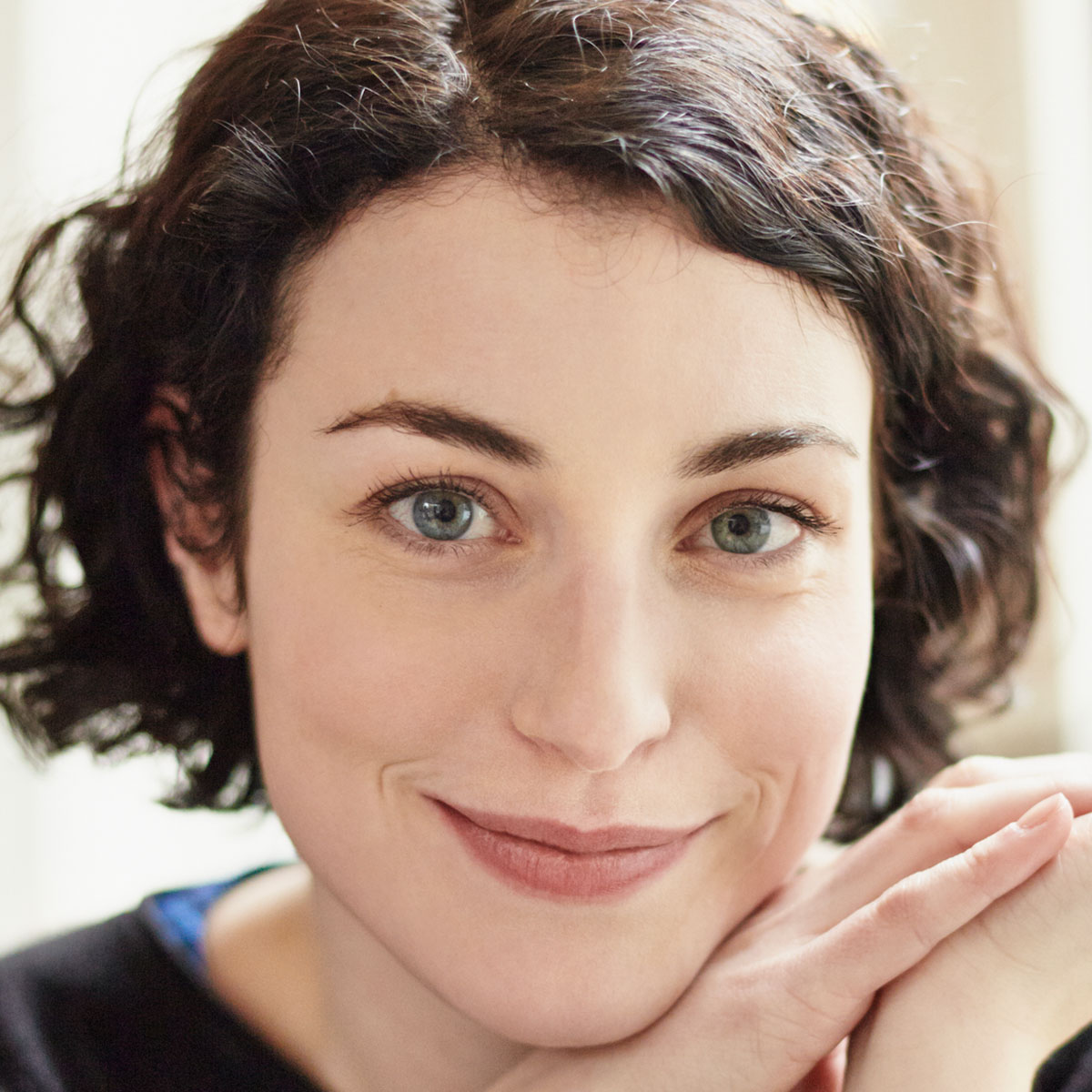 Frau mit braunen lockigen Haaren lächelt