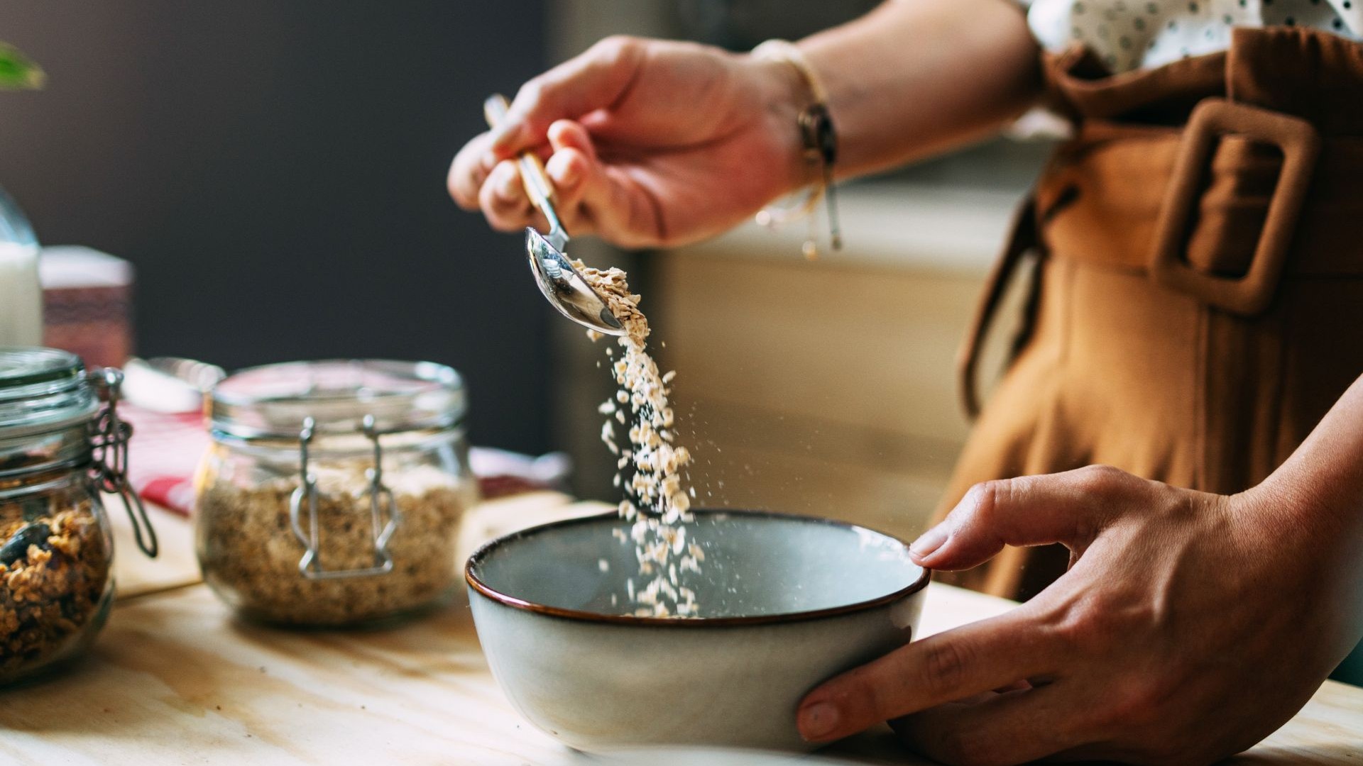 Frau streut Haferflocken in eine Schale