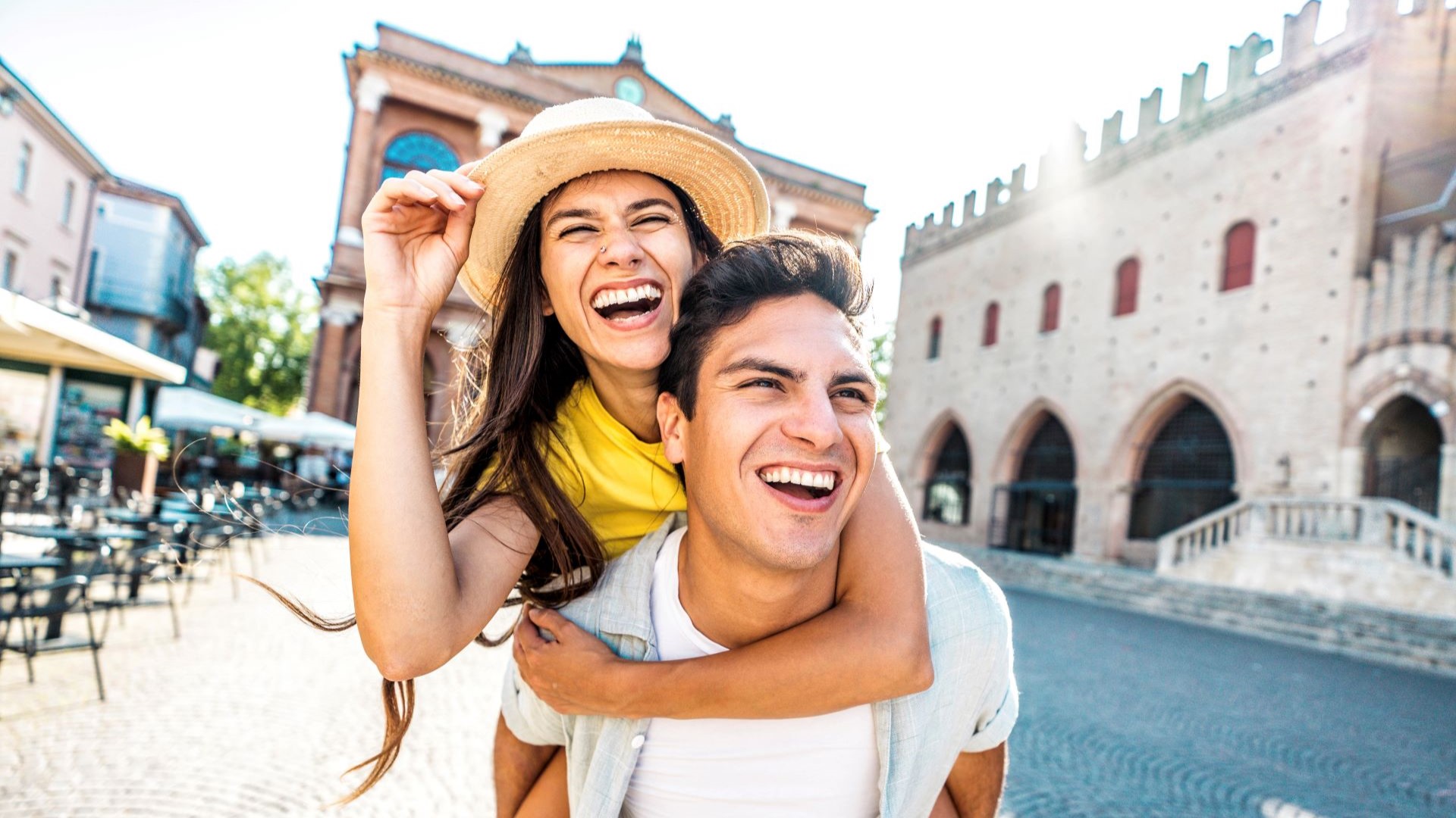 Braunhaarige Frau mit Hut und braunhaariger Mann lachen