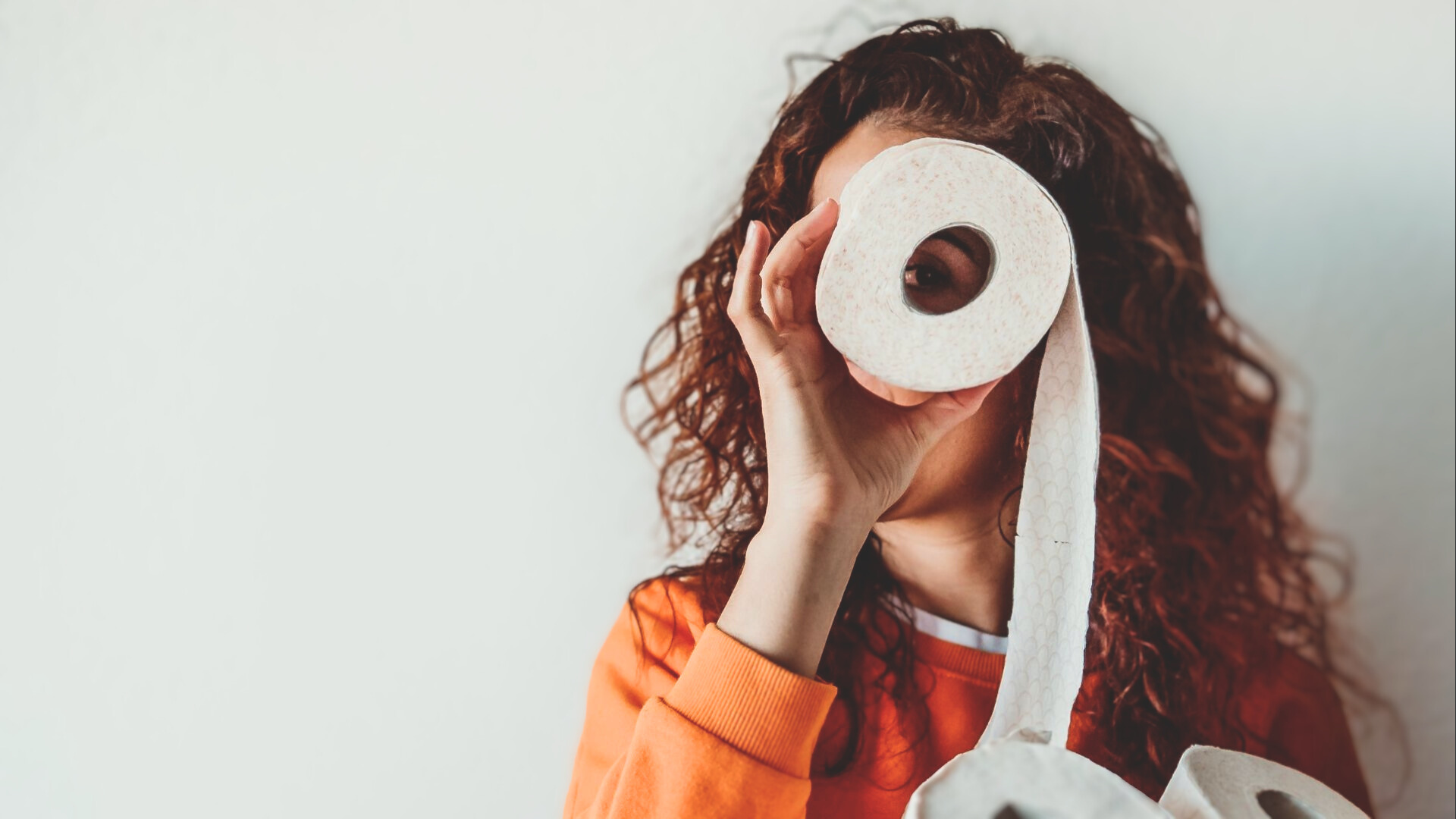 Frau hält Toilettenpapier vor ihr Gesicht