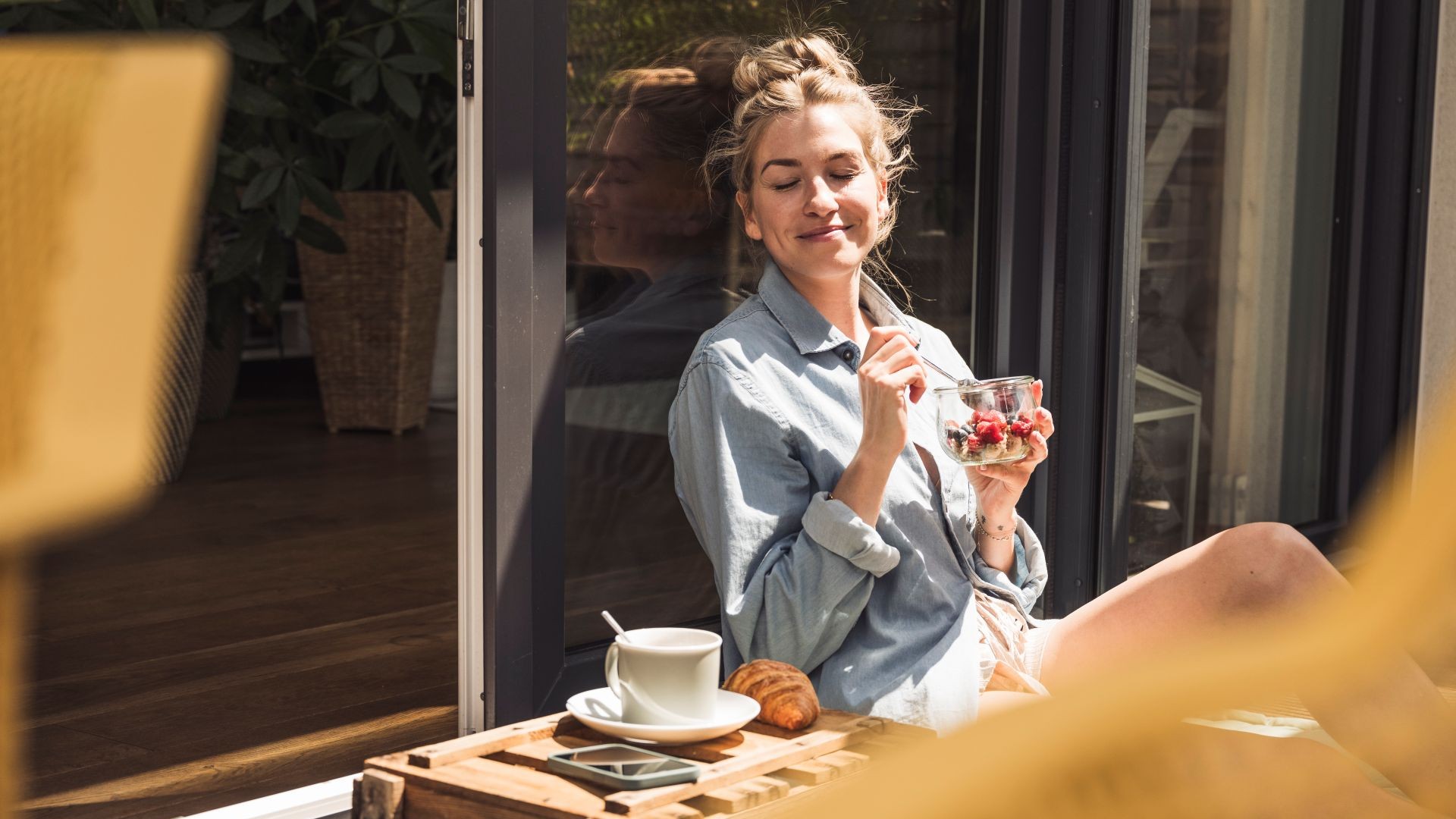 Rothaarige Frau sitzt in Schneidersitz auf einem Sofa und entspannt