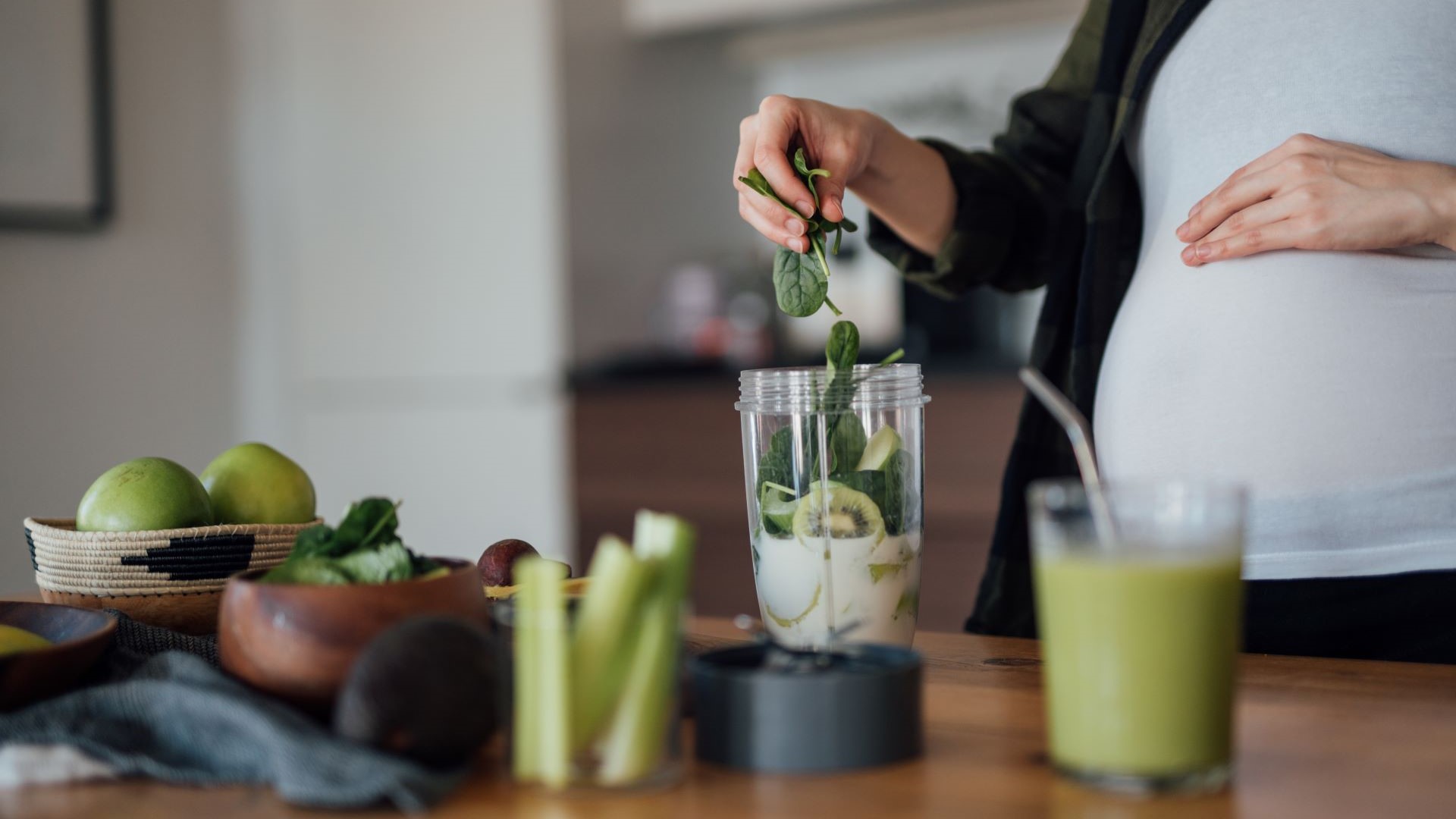 Schwangere Frau bereitet sich einen Smoothie in einem Mixer zu
