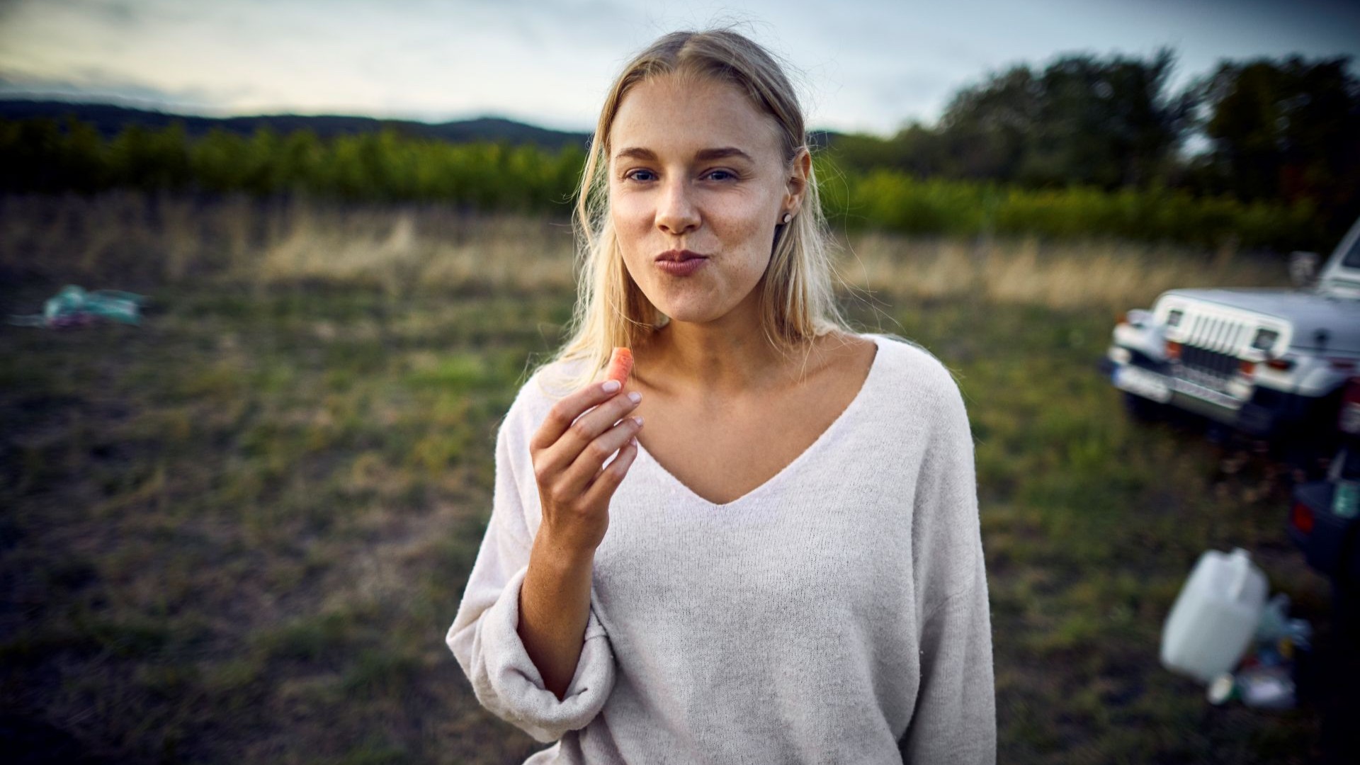Blonde Frau beißt glücklich von einer Möhre ab